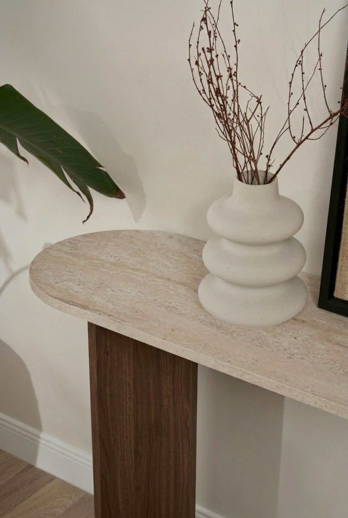 Modern oval side table with a travertine look top and walnut melamine base. Stylish minimalist design.